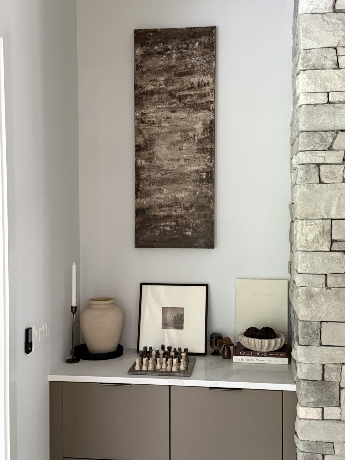 A small vertical painting hung in a styled corner of a home